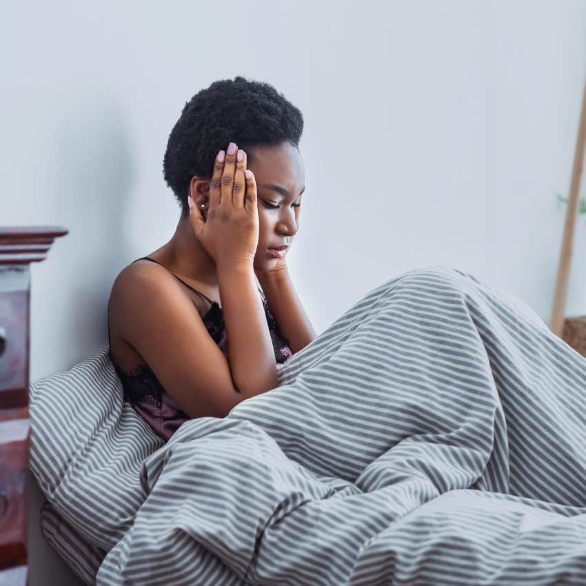 woman in bed with hands on her temples