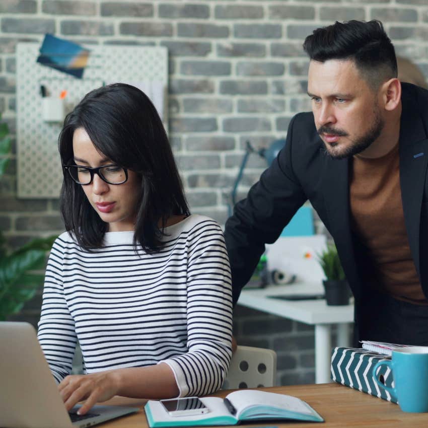 man looking over woman's shoulder at work