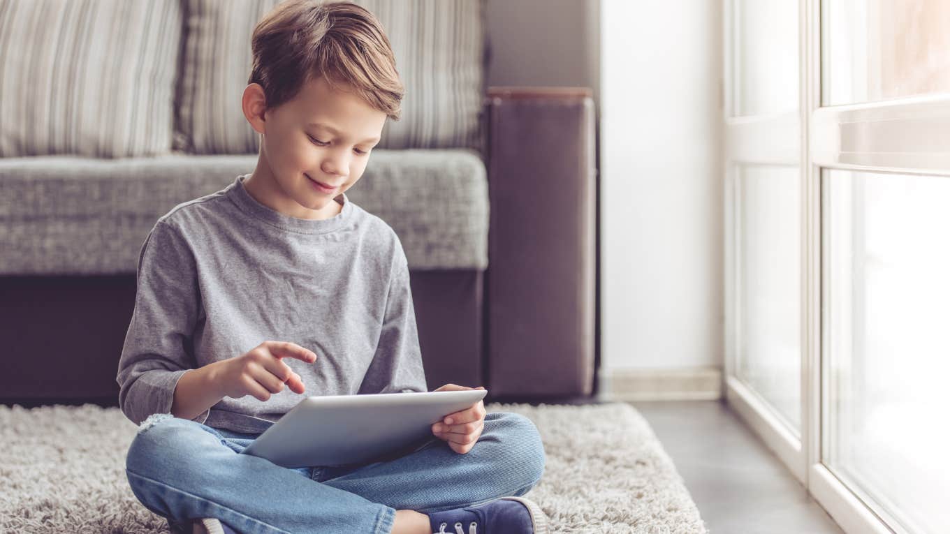 Little boy smiling while playing with digital tablet at home