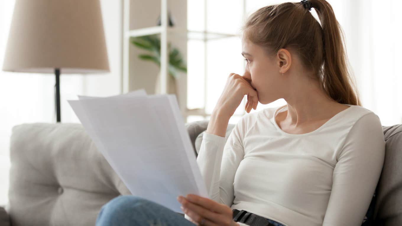 Adult Feels Sick & Throws Mom’s Baby Book After Reading An Entry She Wrote Woman reading baby book papers and looking upset.