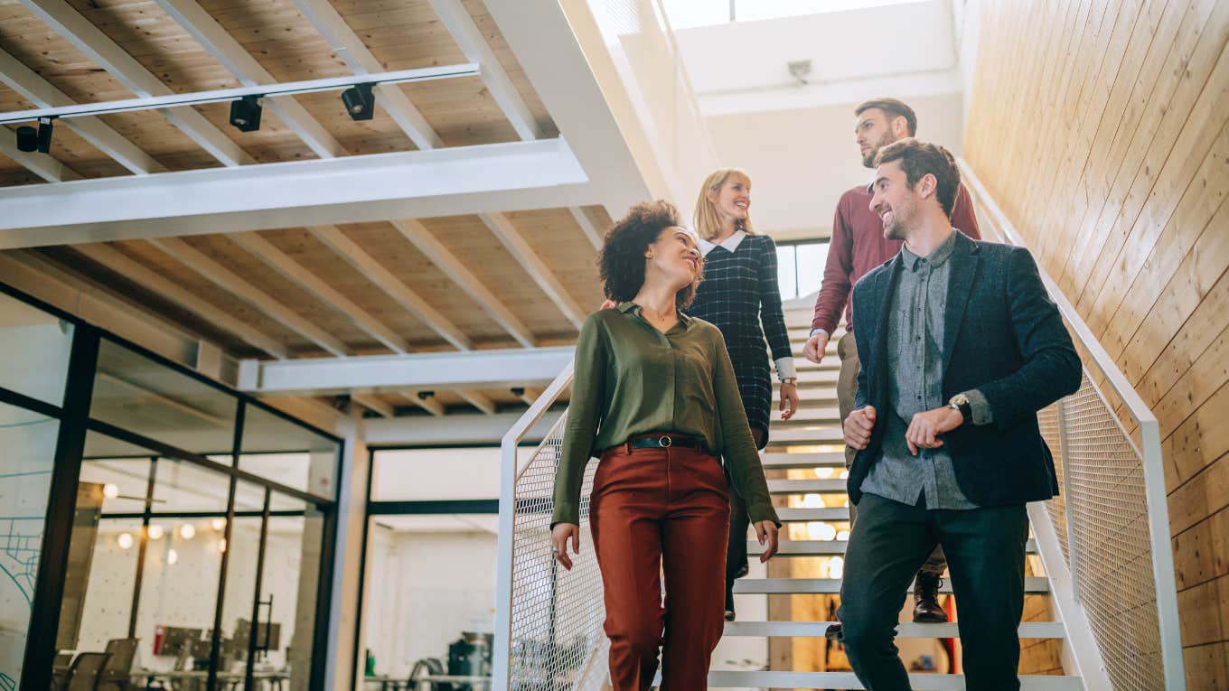 Woman Says Being Antisocial At Work Is A Privilege Only Reserved For People Who Are Excellent At Their Jobs Group of diverse coworkers talking while walking down the stairs in an office