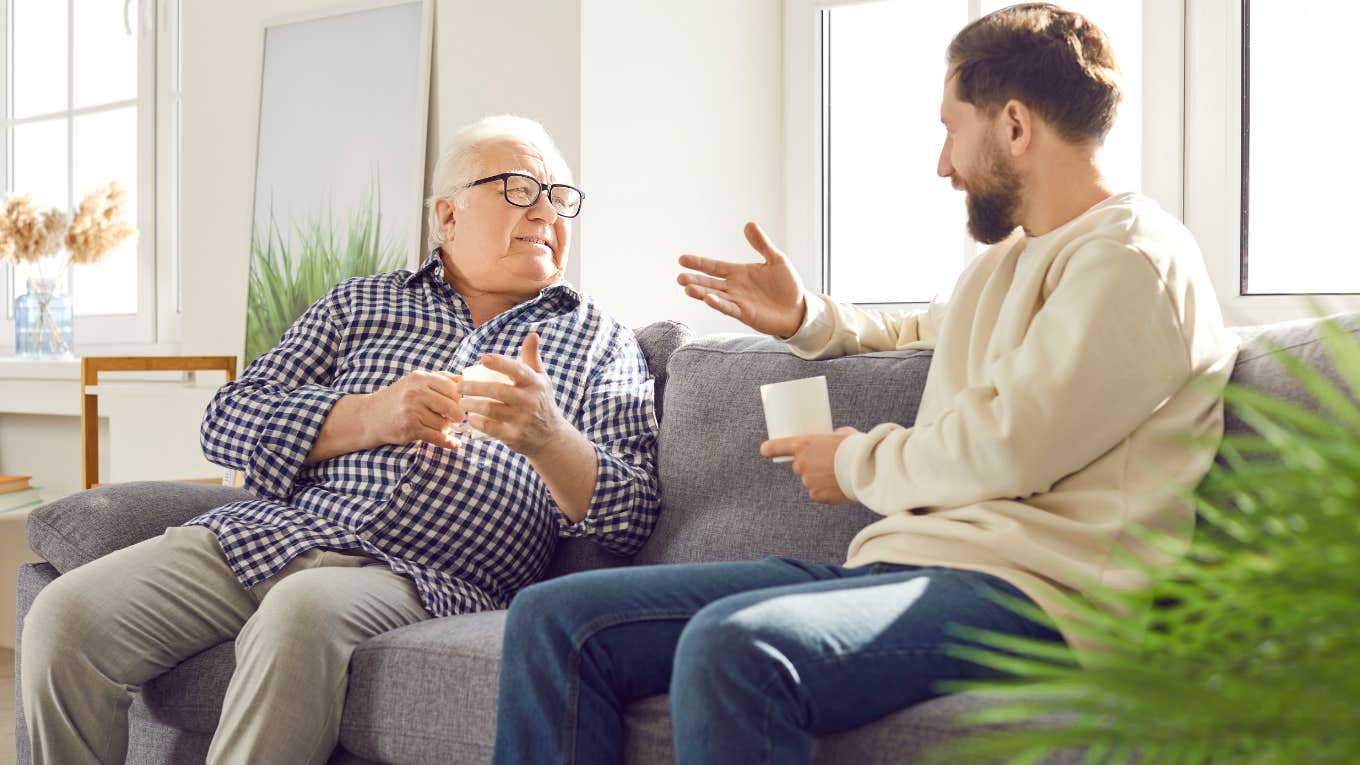 ‘Boomer Dad’ Wants To Go To Homeless Shelter Instead Of Paying Rent Boomer dad and adult son talking on the couch.
