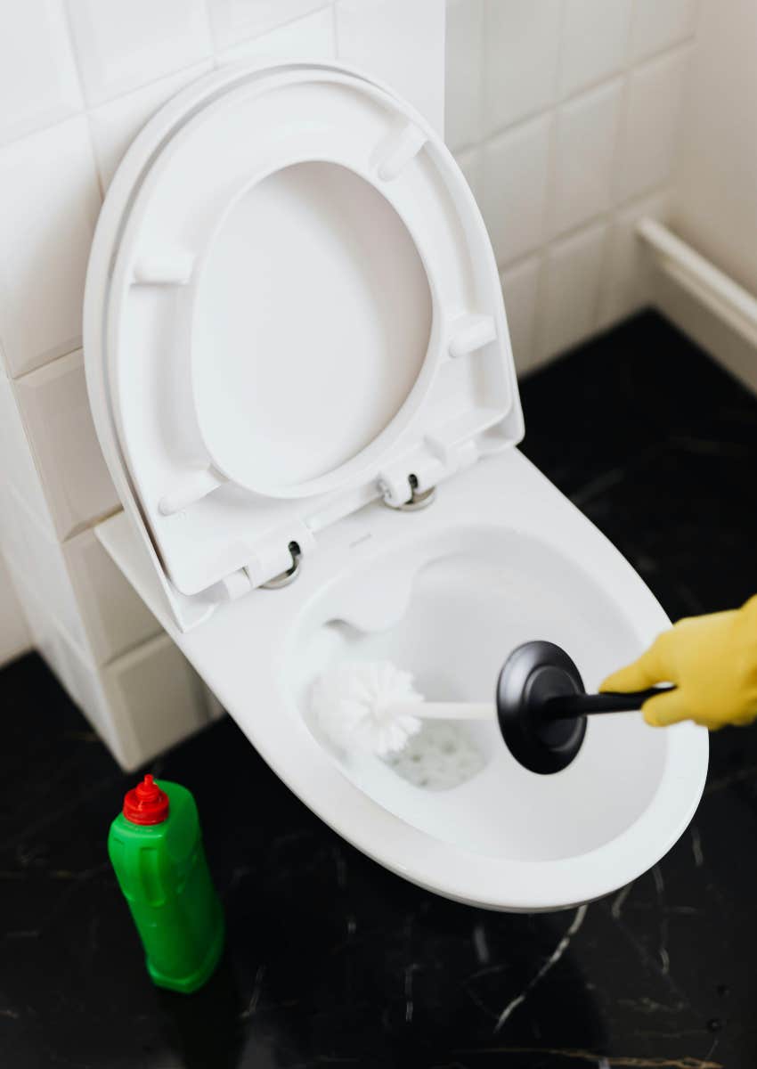 hand using a brush to clean a toilet