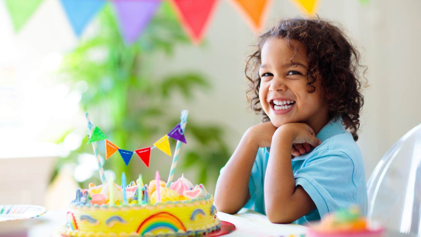 Dad Pours Champagne On His Daughter’s Head To Celebrate Her 3rd Birthday Party little girl smiles in front of her birthday cake at her birthday party