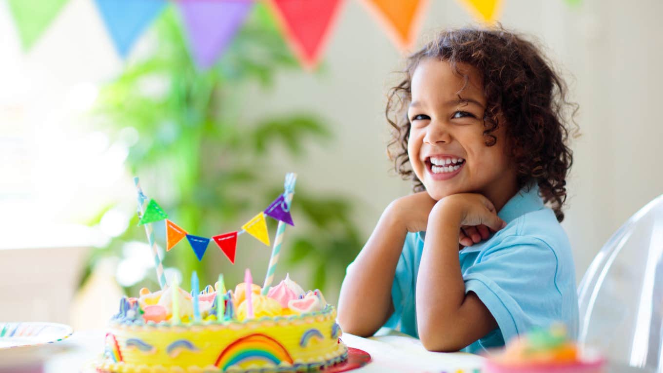 little girl smiles in front of her birthday cake at her birthday party