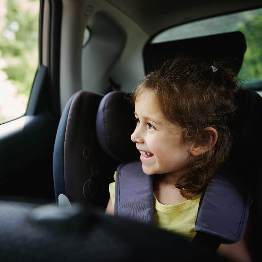 Happy girl in booster seat in car