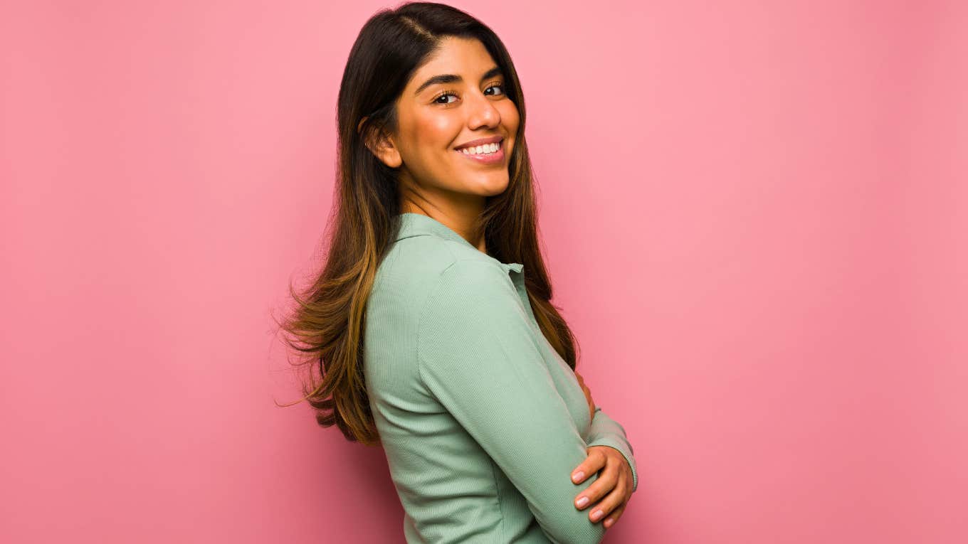 secure woman smiling in front of pink background