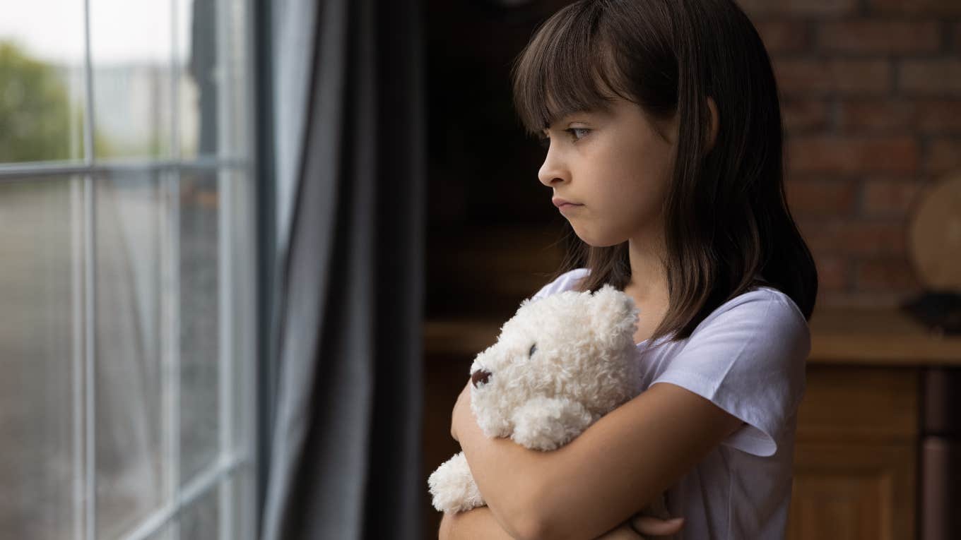 Little girl waiting by the window for her dad to pick her up after he promised to be there