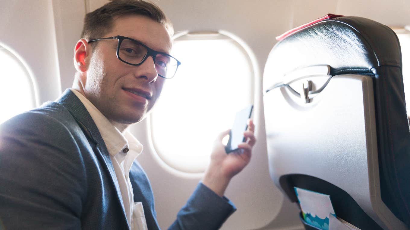 man on airplane using his phone