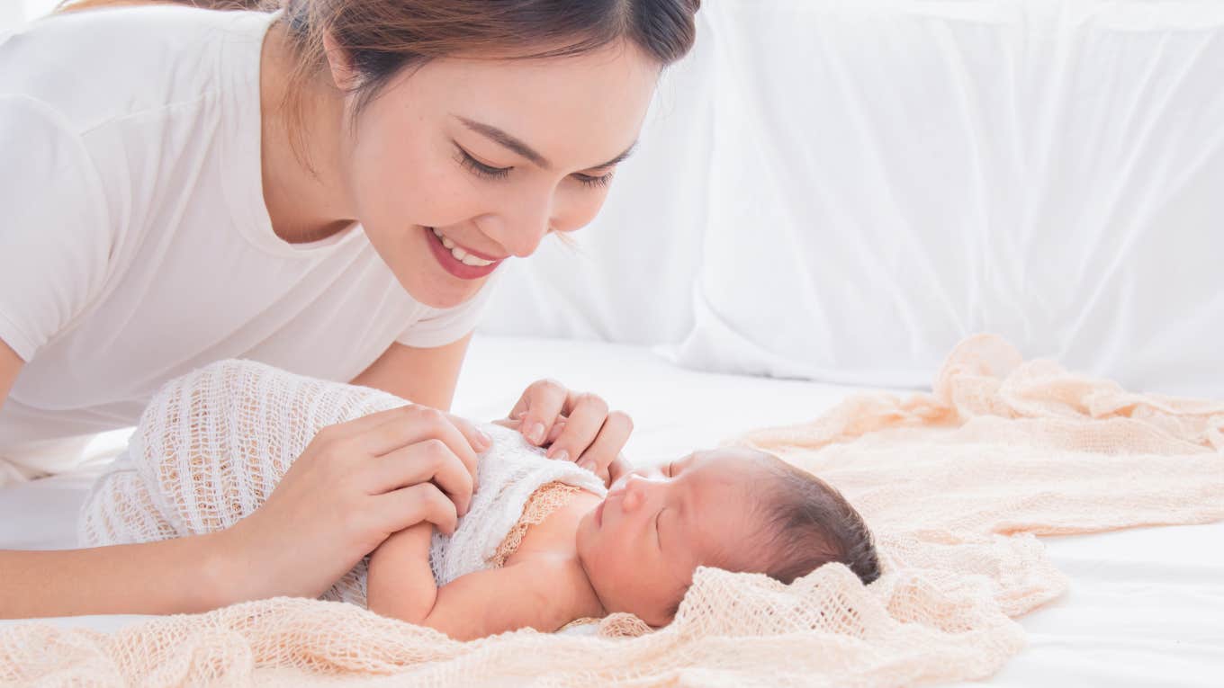 Man Refuses To Let Girlfriend Be A Stay-At-Home Mom mom with baby swaddled on bed