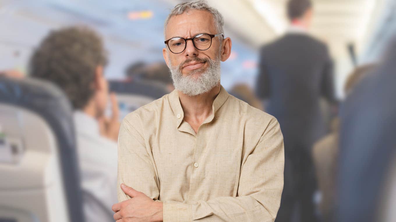 Man Refuses To Let Other Passenger Sit In Empty Seat He Paid For Airline passenger stands angrily in airplane aisle.