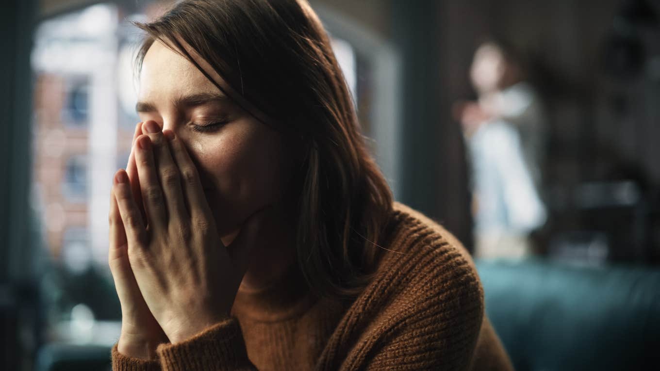 Man Steals Girlfriend's Inheritance To Pay His Bills woman sitting on a couch crying while man argues with her
