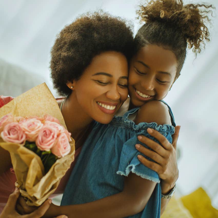 mother and daughter hugging with a bouquet of roses