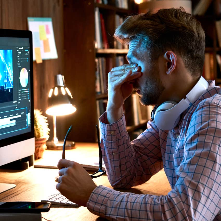 Overworked man sitting at his laptop in the dark. 