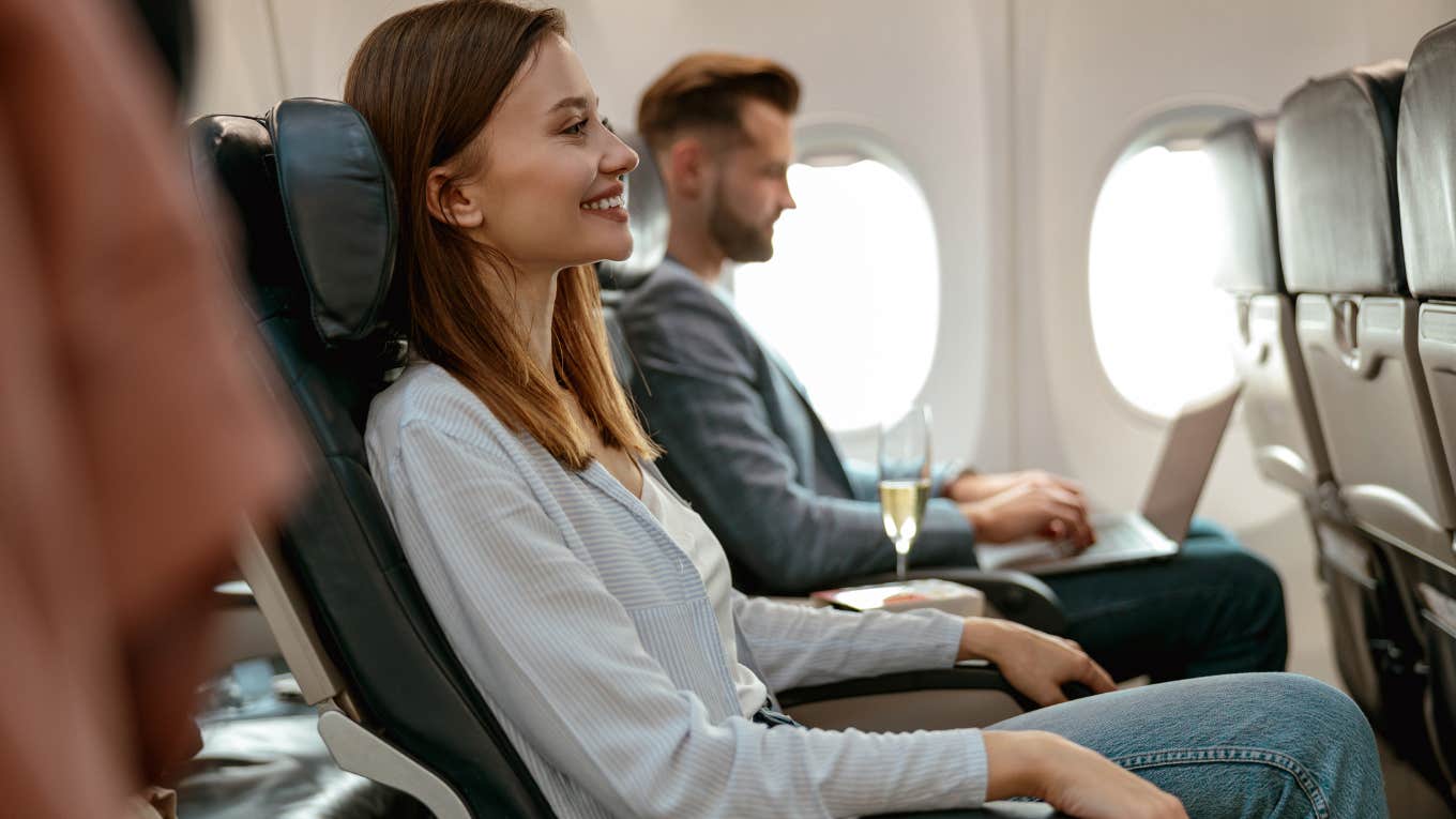 Passenger Accuses Man Of Violating Her Personal Space After He's Forced To Climb Over Her To Use The Bathroom Cheerful woman sitting in seat in airplane next to man on laptop
