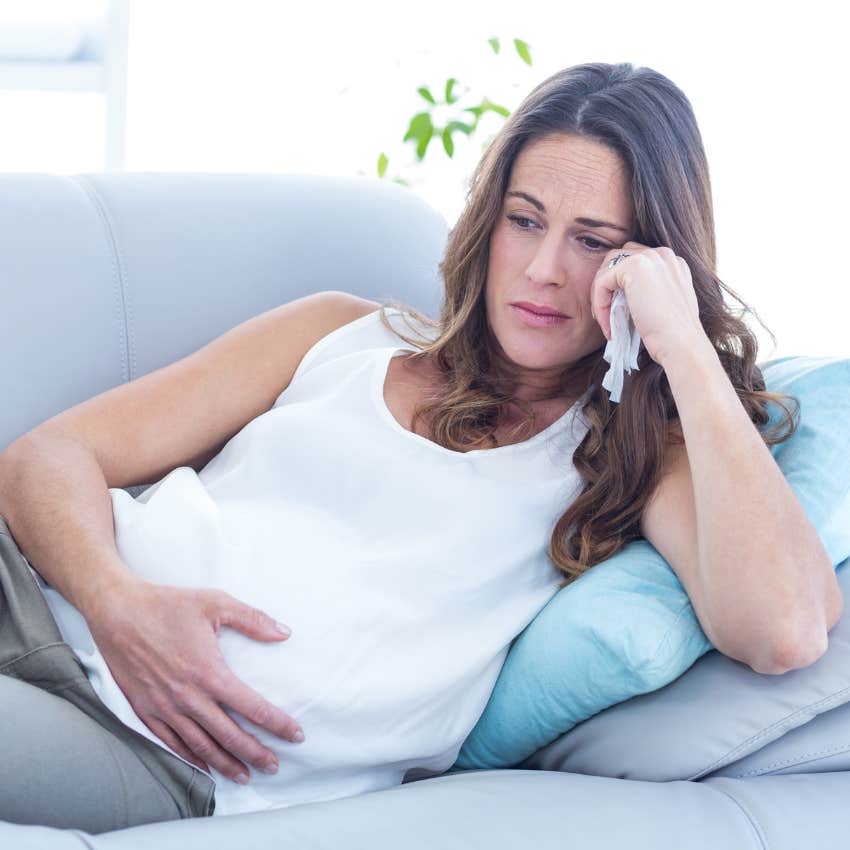 Sad pregnant woman laying on couch. 