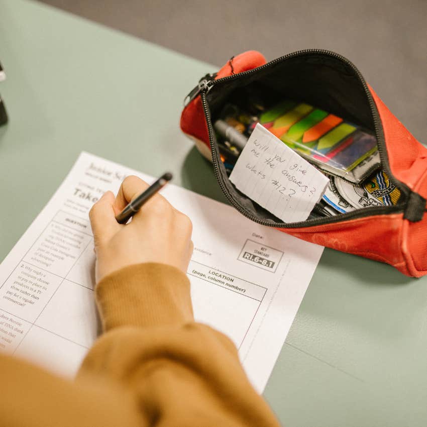 Student writing on a test paper. 