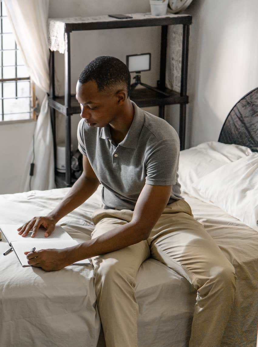 Man on bed writing love notes