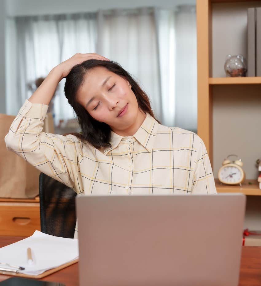 Woman at laptop is trying to relax her stiff neck