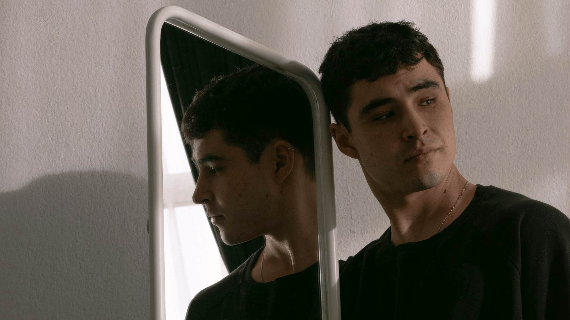 man feeling guilty in front of mirror