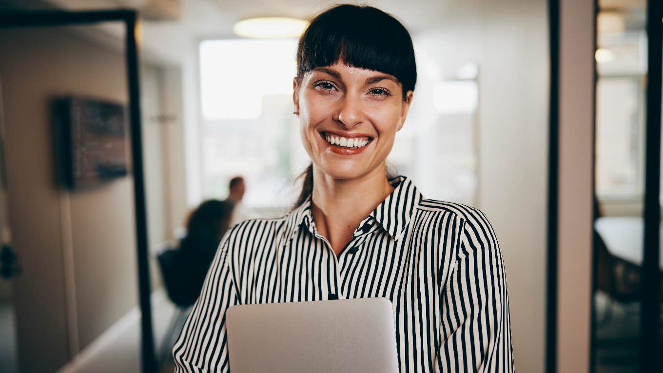 accomplished woman smiling holding computer