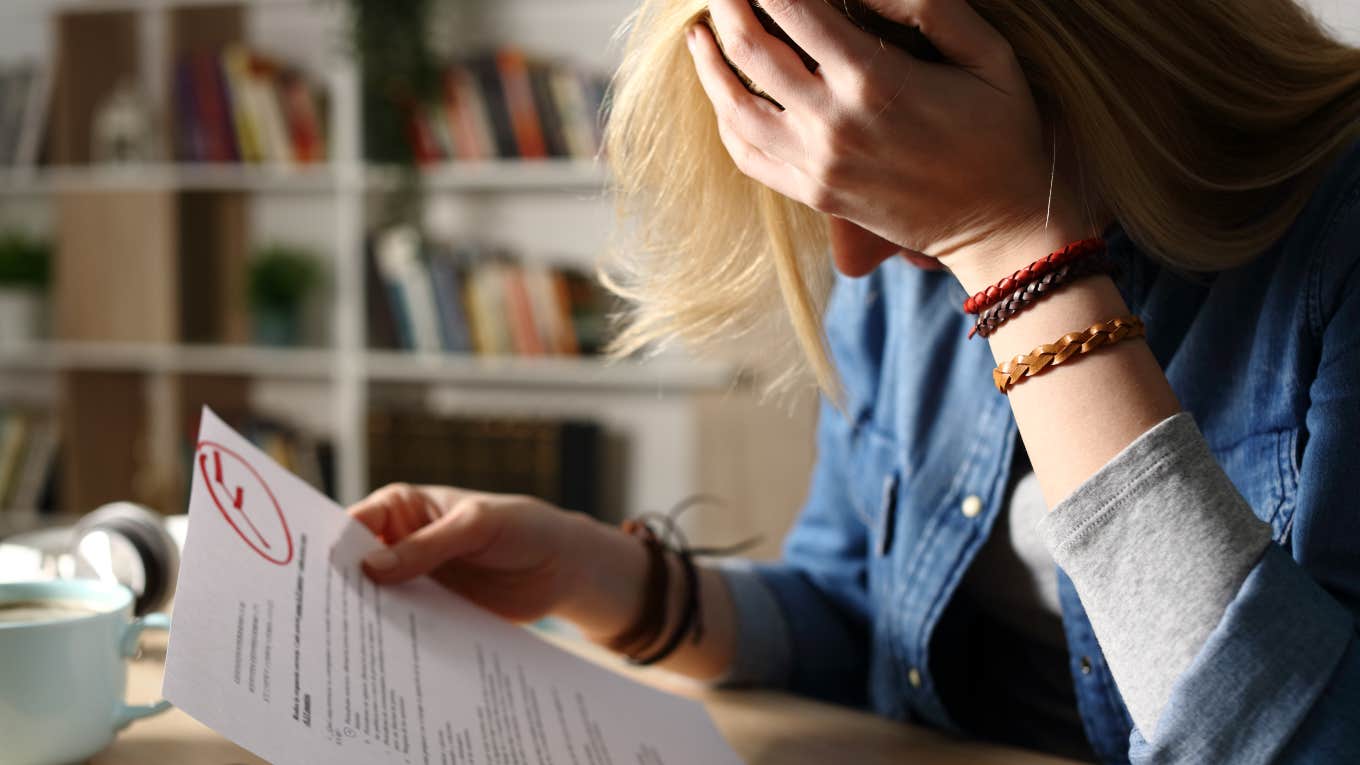 Student Accuses Teacher Of 'Hater Behavior' girl holding paper with F grade frustrated