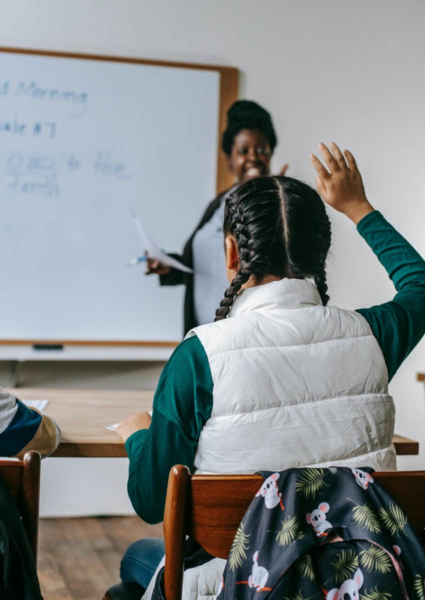 smiling teacher calling on student with raised hand