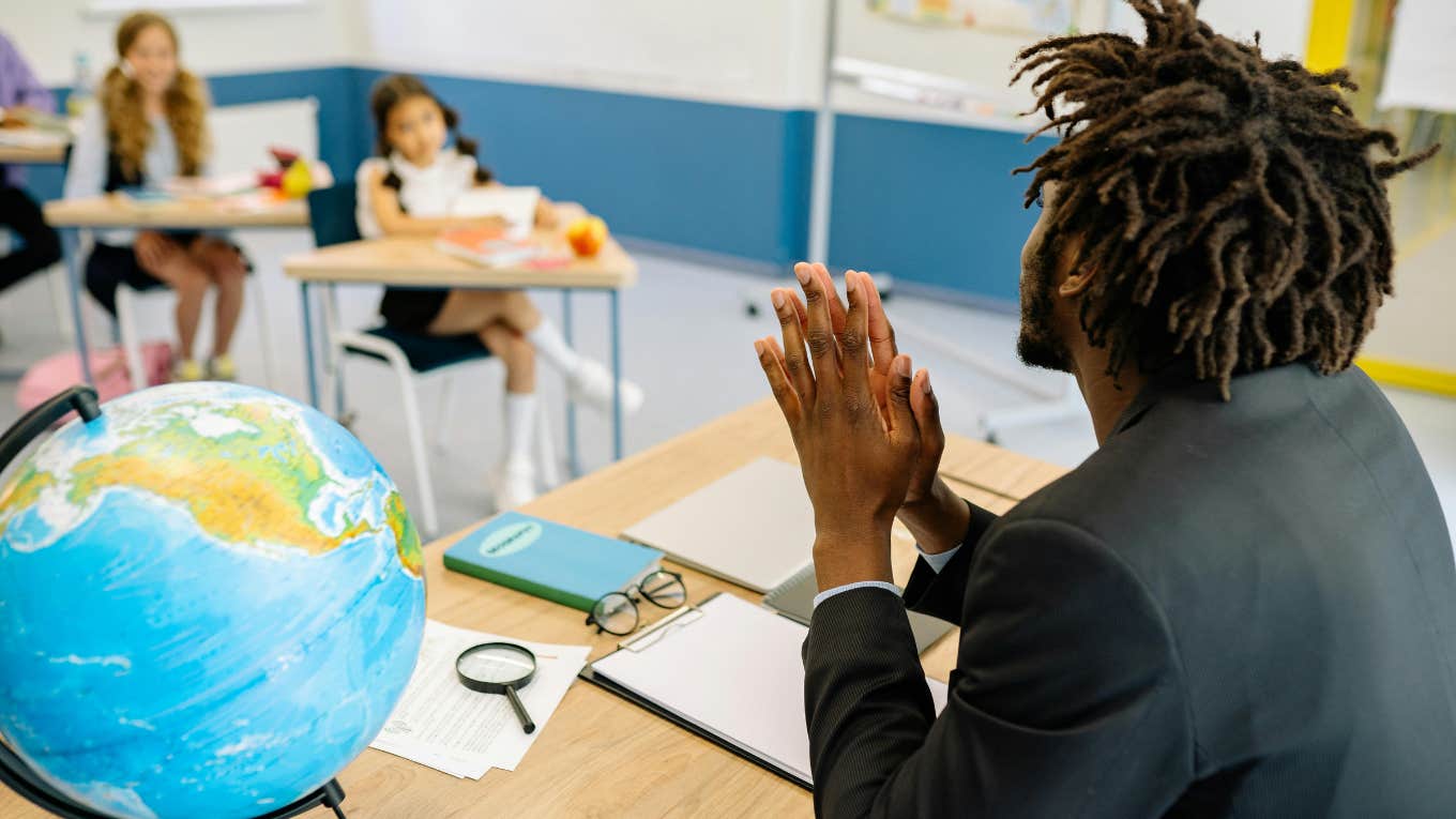 teacher sitting and facing students in classroom