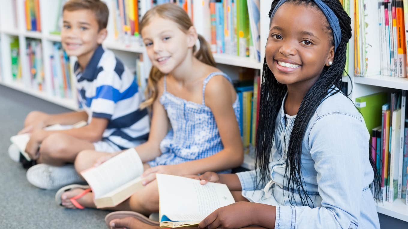 group of kids reading books on floor of library