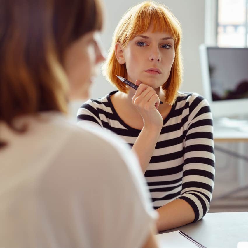 Unhappy woman sitting with her coworker. 