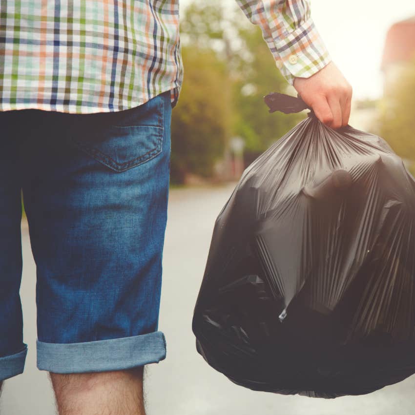 young man taking out garbage in black plastic bag