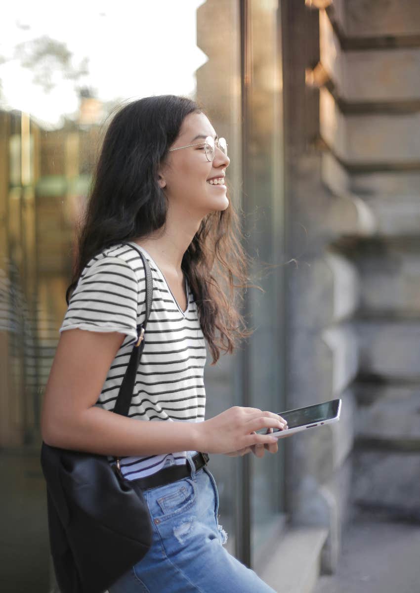 woman standing in front of store on her phone
