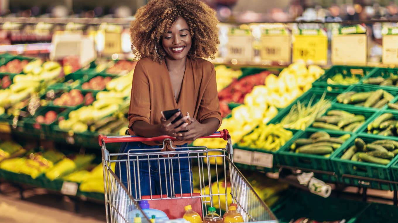 woman on phone with cart in grocery store