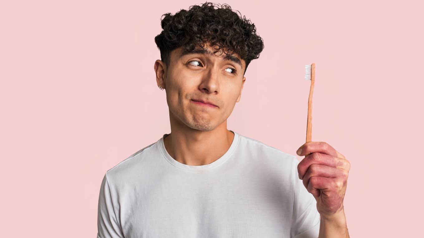 Woman Says Her Fiancé Has Refused To Brush His Teeth For 6 Years Man refusing to brush his teeth while looking at toothbrush.