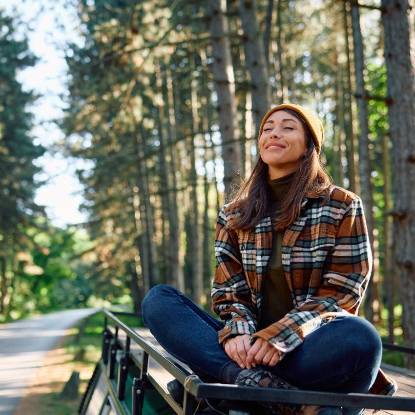 Woman smiling while sitting on top of a car. 
