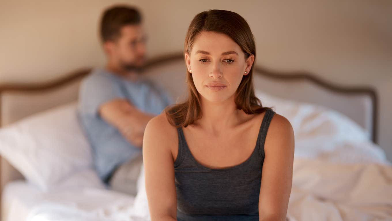 sad woman sitting on bed with husband 