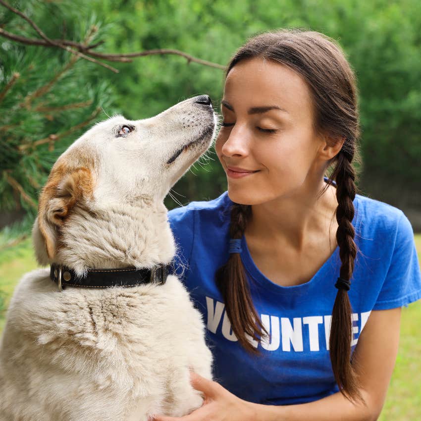 Woman volunteering at an animal shelter, playing with dog