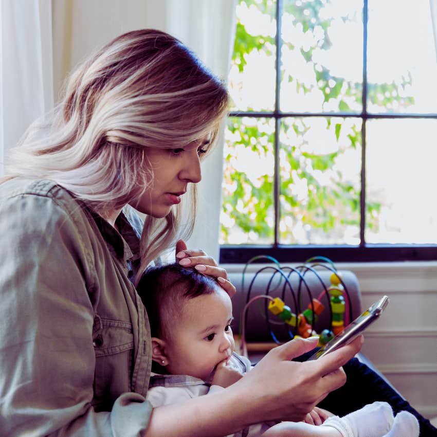 worried mom texting with baby in her lap