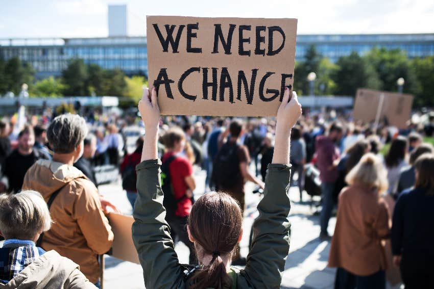 protester holding up a sign about change because american dream is dead