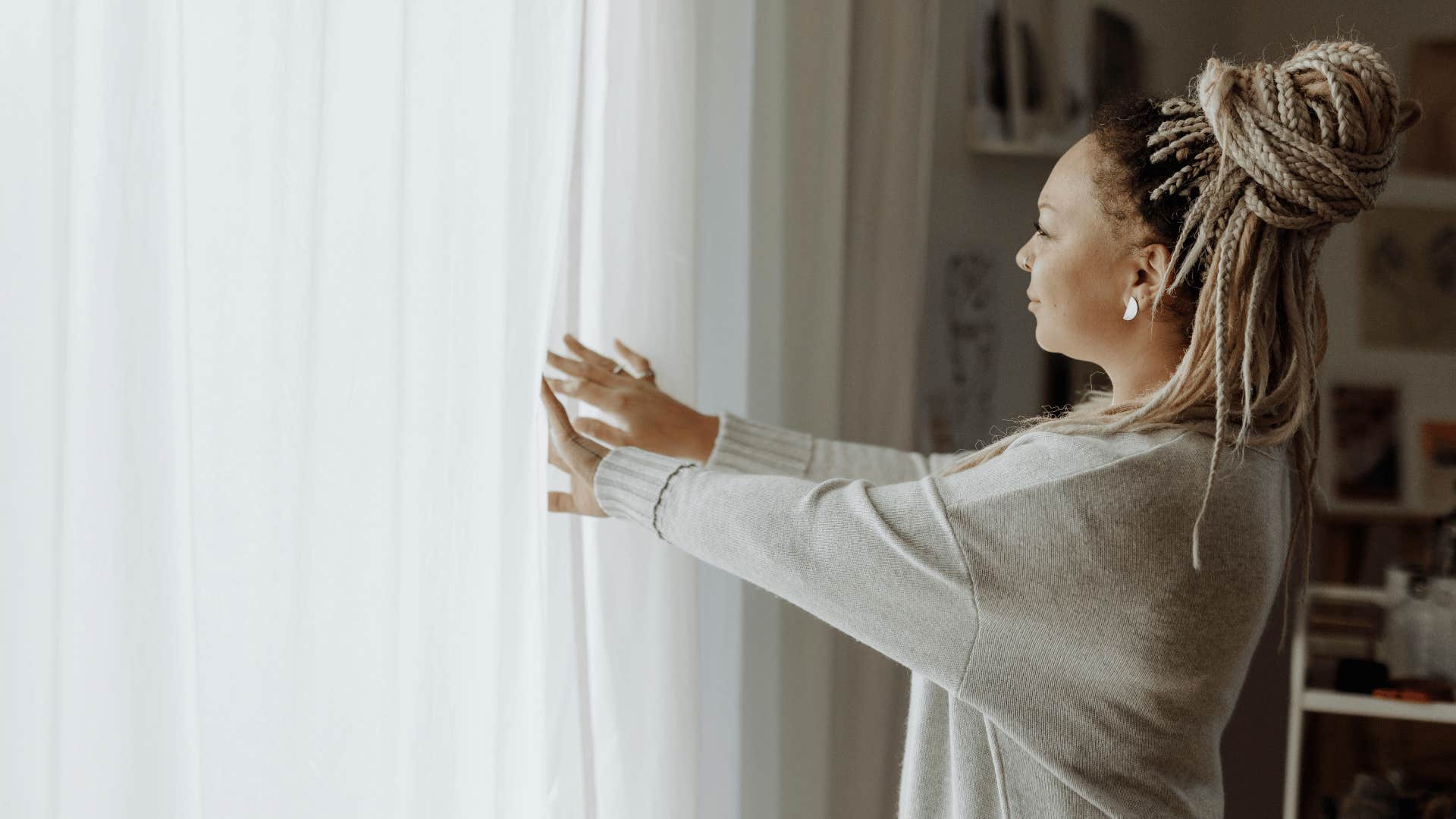 woman opening curtains