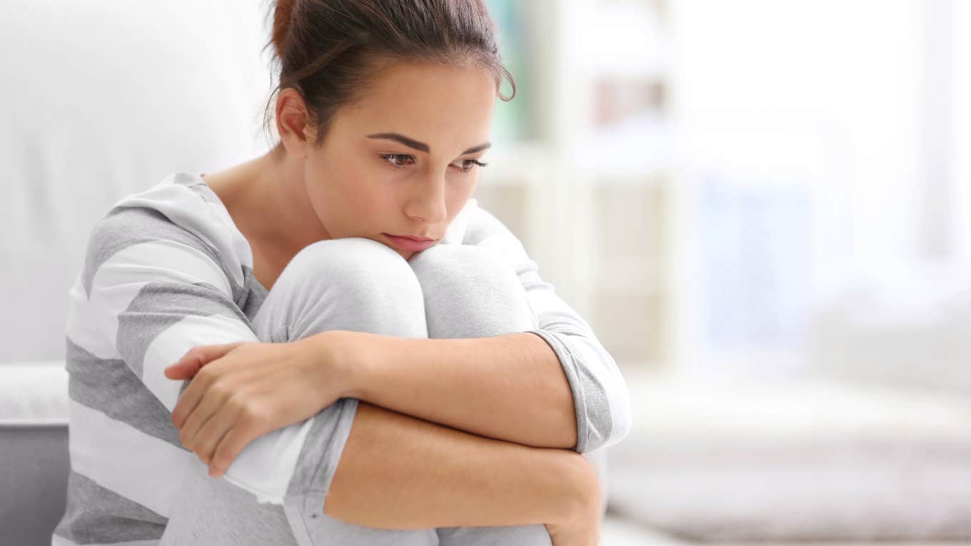 A Phrase That's A Red Flag For Hidden Unhappiness woman hugging knees looking upset