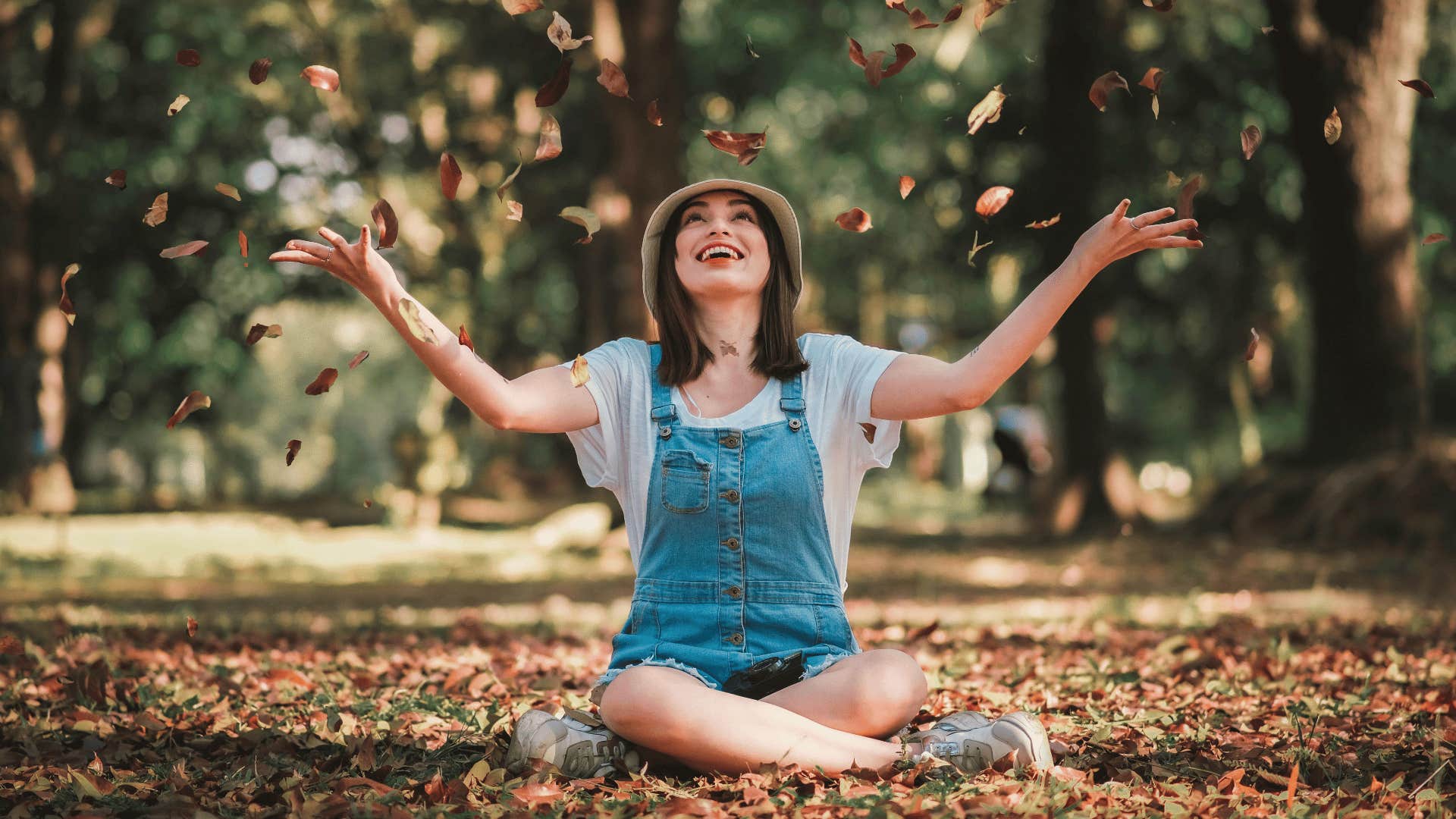 positive woman playing with leaves