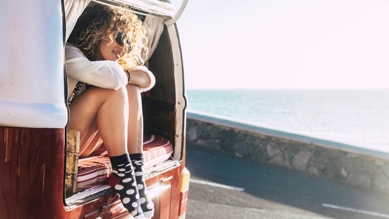woman sits in back of van admiring ocean view