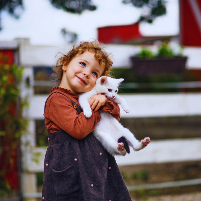 toddler hugging a white cat