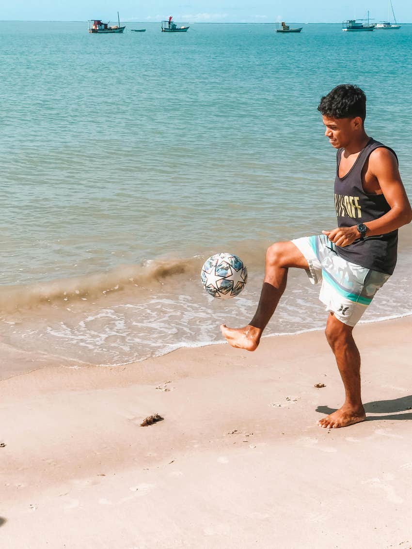 man alone on beach playing soccer