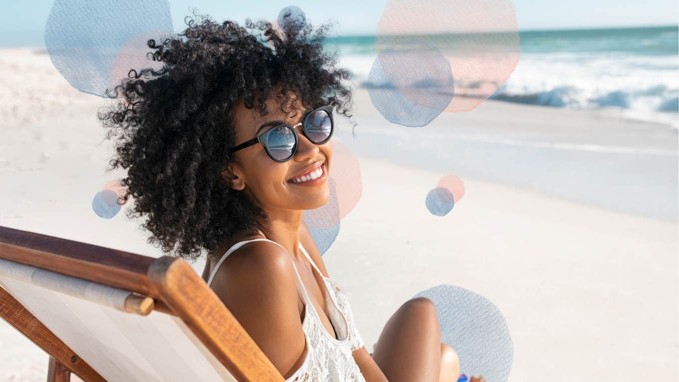 Happy Black woman with natural curly hair living her dream life on a beach