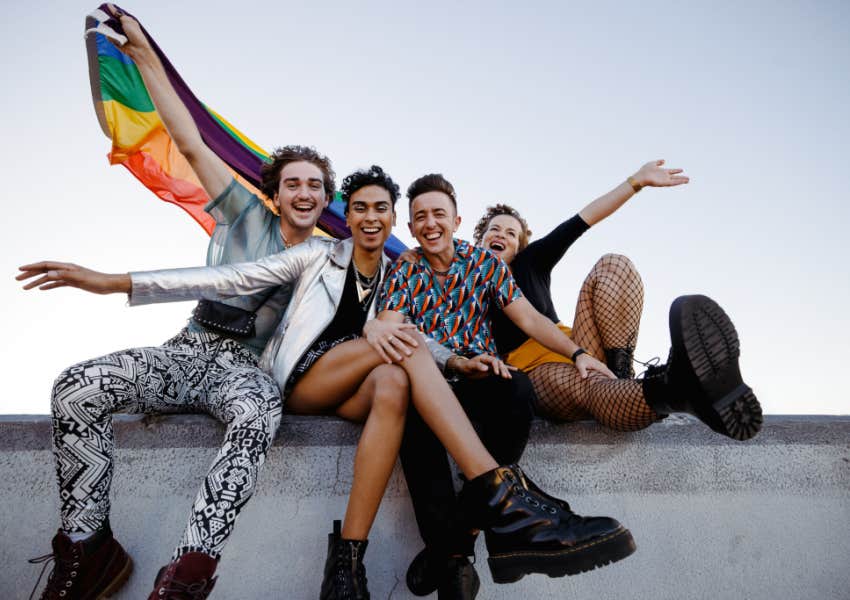 queer and trans friends laugh and wave pride flag 