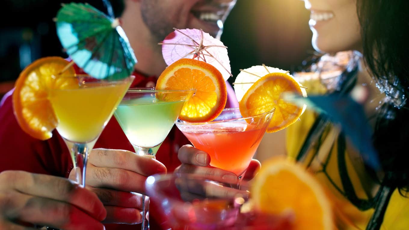 man and woman holding fruity cocktails