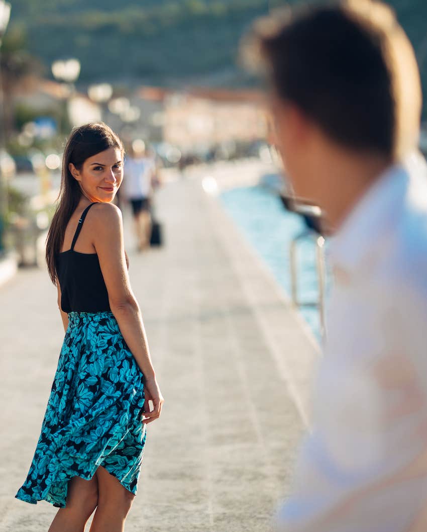 She looks back for him to pursue from a distance