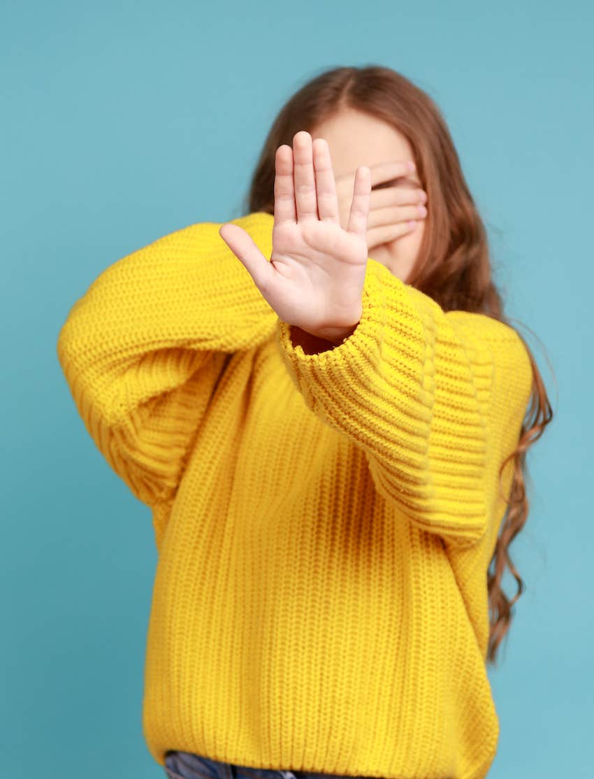 Eyes covered, hand up, she sabotages her initimate life